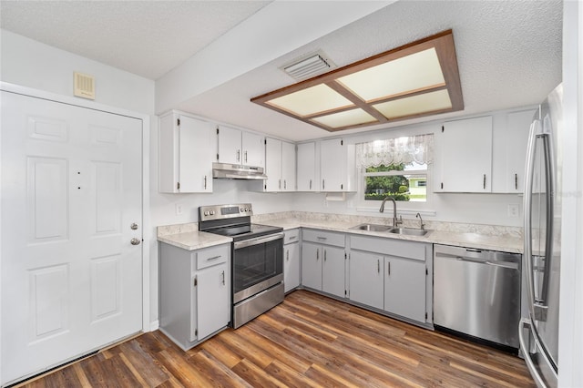 kitchen featuring dark wood-style floors, stainless steel appliances, light countertops, under cabinet range hood, and a sink