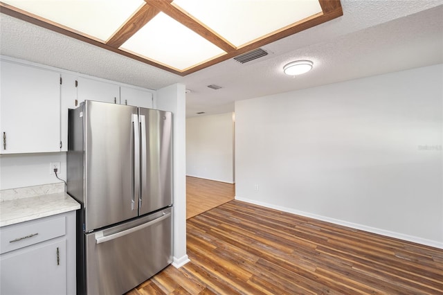 kitchen featuring a textured ceiling, dark wood-type flooring, visible vents, light countertops, and freestanding refrigerator