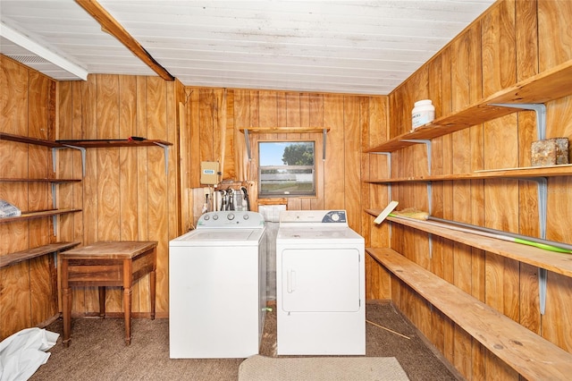 clothes washing area featuring washer and dryer, dark carpet, and wooden walls