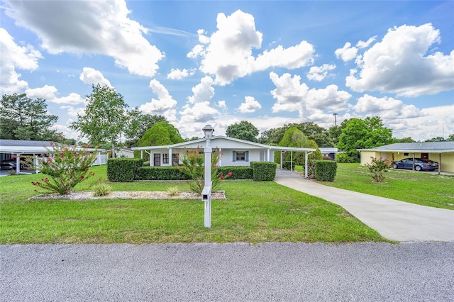 ranch-style home with driveway, an attached carport, and a front yard