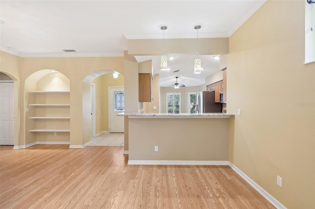 kitchen featuring light wood-type flooring, kitchen peninsula, decorative light fixtures, and stainless steel fridge