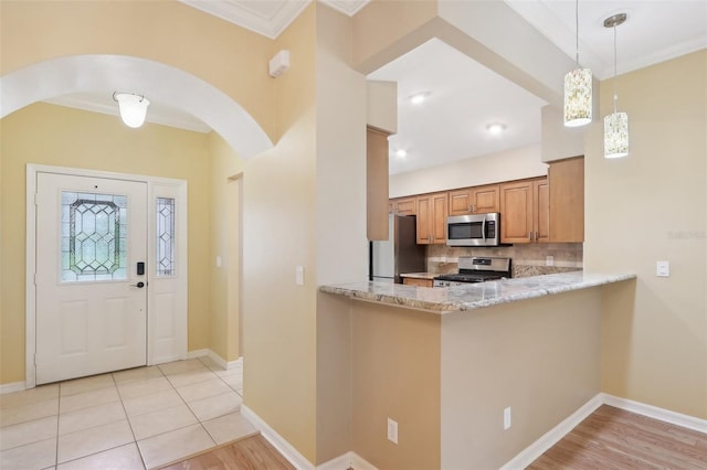 kitchen featuring light wood-type flooring, backsplash, light stone counters, and stainless steel appliances