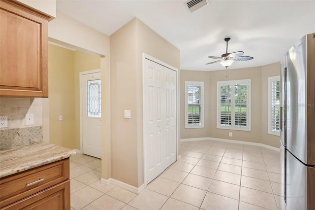 kitchen with decorative backsplash, light stone counters, stainless steel fridge with ice dispenser, light tile patterned floors, and ceiling fan