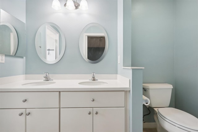 bathroom with toilet and double sink vanity