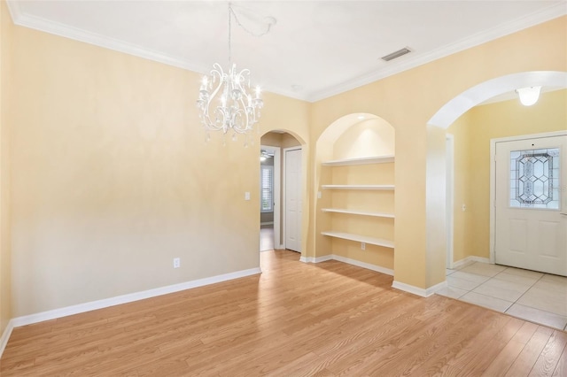 foyer with a notable chandelier, light tile patterned floors, and ornamental molding