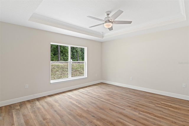 unfurnished room with ceiling fan, hardwood / wood-style floors, ornamental molding, and a raised ceiling