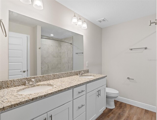 bathroom featuring toilet, tiled shower, wood-type flooring, a textured ceiling, and vanity