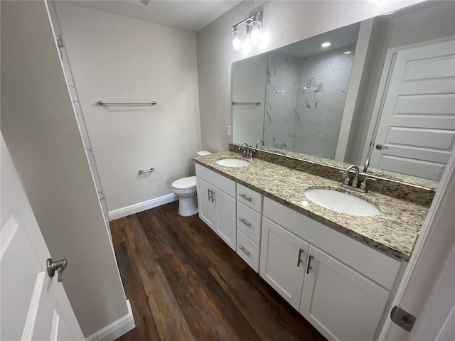 bathroom featuring toilet, vanity, wood-type flooring, and a shower