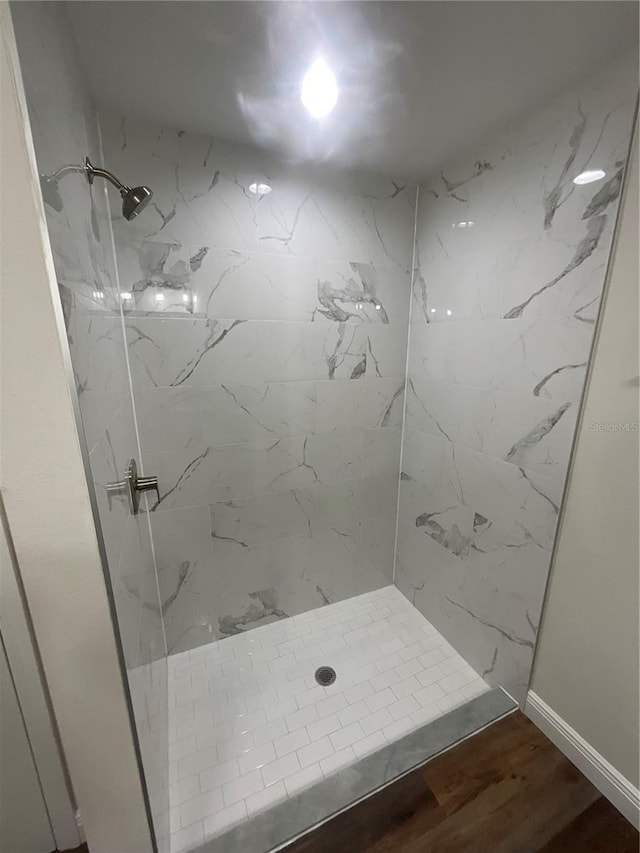 bathroom with hardwood / wood-style floors and a tile shower