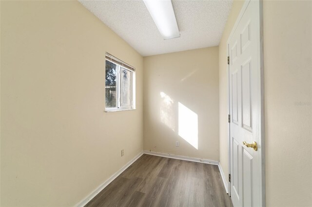 unfurnished room featuring dark wood-type flooring and a textured ceiling