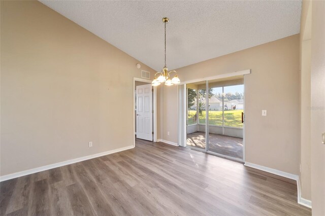 unfurnished dining area with hardwood / wood-style flooring, a chandelier, vaulted ceiling, and a textured ceiling