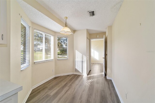 unfurnished dining area with hardwood / wood-style flooring and a textured ceiling