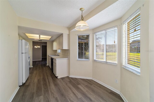 kitchen with sink, dark hardwood / wood-style flooring, white fridge, pendant lighting, and white cabinets