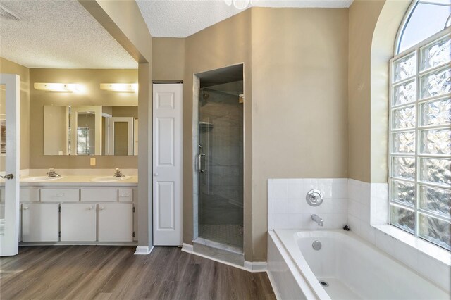 bathroom with hardwood / wood-style flooring, vanity, a wealth of natural light, and a textured ceiling