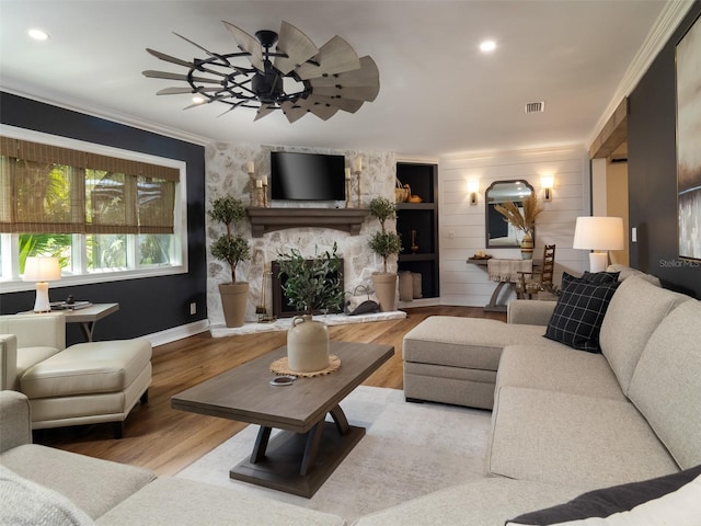 living room with a fireplace, wood-type flooring, crown molding, and ceiling fan