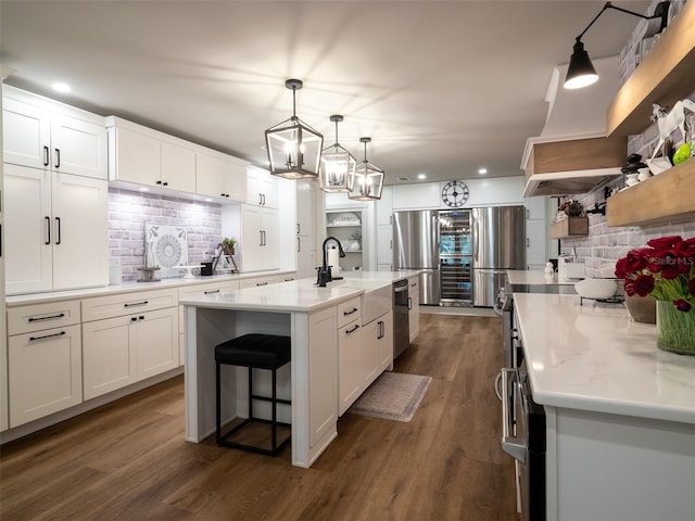 kitchen featuring an island with sink, backsplash, white cabinets, stainless steel fridge, and dark hardwood / wood-style floors