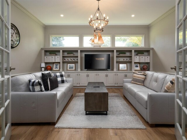 living room featuring a notable chandelier, french doors, light hardwood / wood-style flooring, and ornamental molding