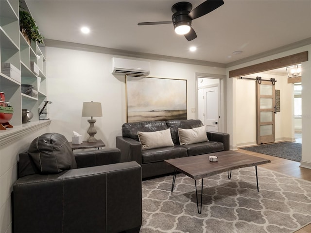 living room with ceiling fan, a barn door, wood-type flooring, and crown molding