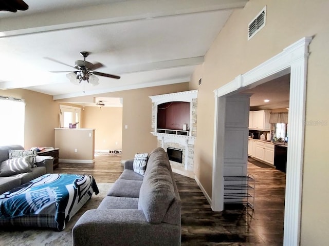 living room with a fireplace, dark hardwood / wood-style floors, ceiling fan, and beamed ceiling