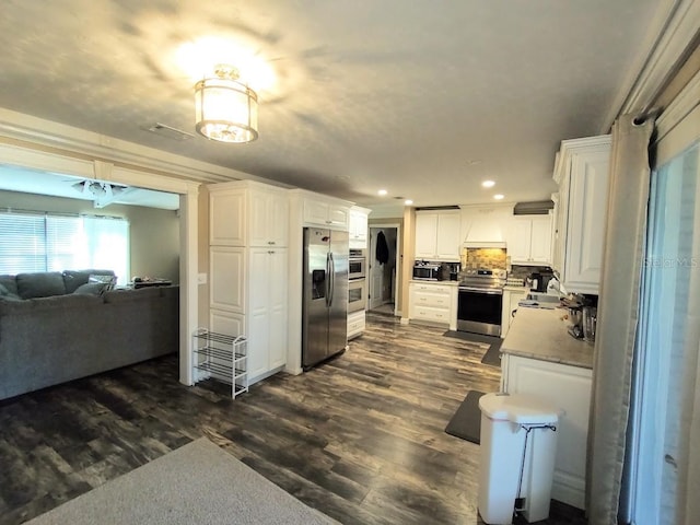 kitchen featuring white cabinets, backsplash, dark wood-type flooring, and appliances with stainless steel finishes