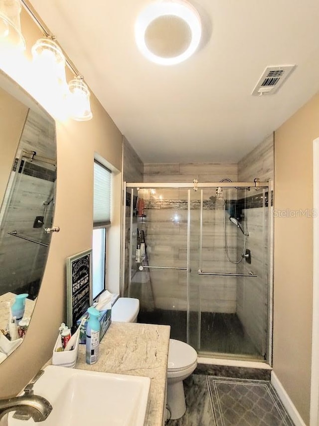 bathroom with a shower with door, vanity, and toilet