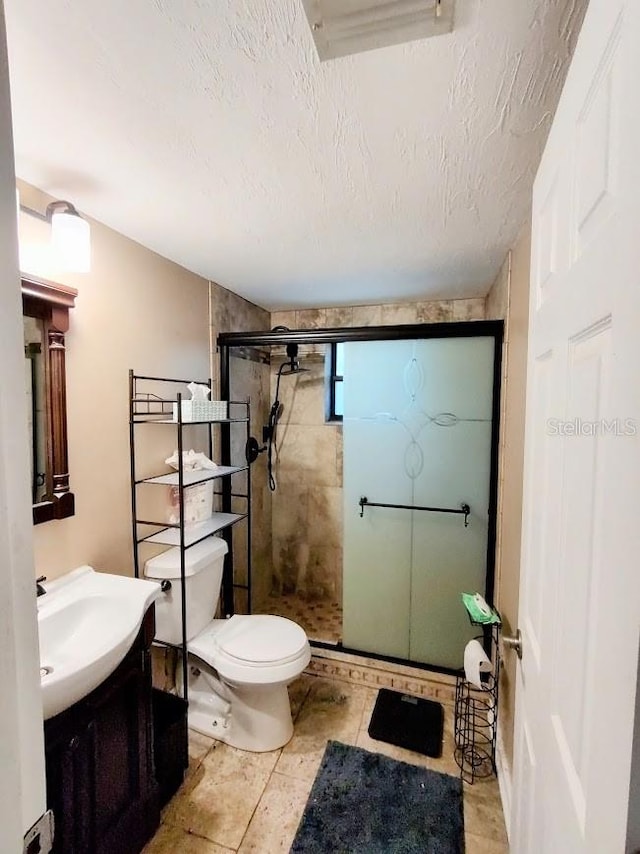 bathroom with tile patterned floors, toilet, a shower with door, and a textured ceiling