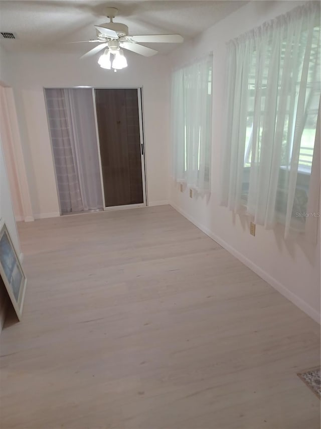 empty room with light wood-type flooring, baseboards, visible vents, and ceiling fan