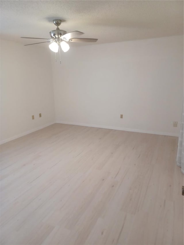 empty room featuring light wood-style floors, ceiling fan, baseboards, and a textured ceiling