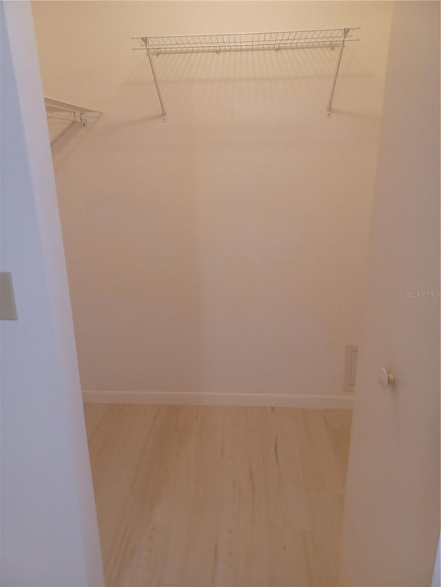 walk in closet with hardwood / wood-style flooring