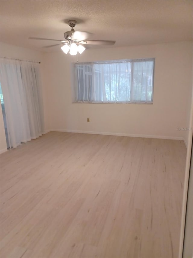 unfurnished room with light wood-style floors, ceiling fan, a textured ceiling, and baseboards