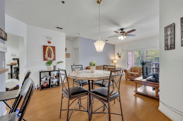 dining area featuring ceiling fan, a textured ceiling, and light hardwood / wood-style floors