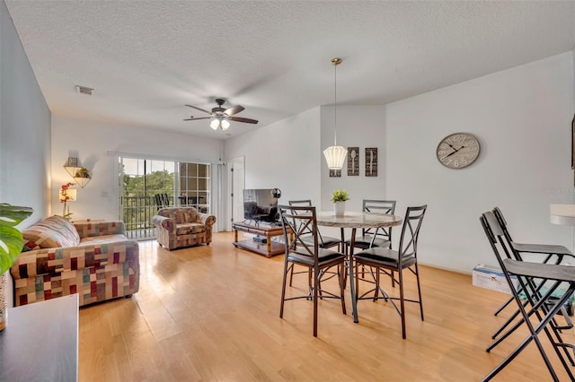 dining space with ceiling fan, a textured ceiling, and light hardwood / wood-style floors