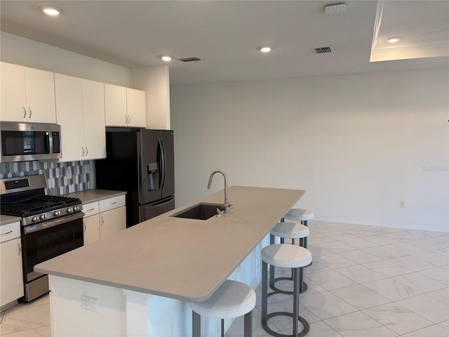 kitchen featuring a center island with sink, white cabinetry, a breakfast bar area, and appliances with stainless steel finishes