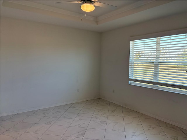 empty room with a raised ceiling, crown molding, and ceiling fan