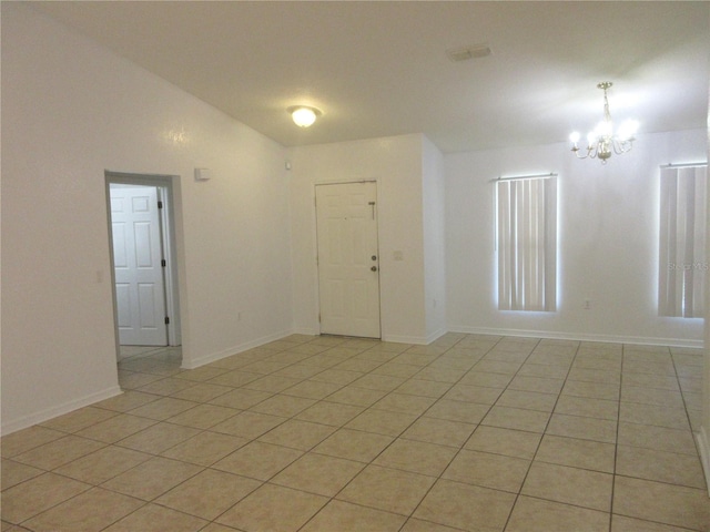 spare room with light tile patterned flooring, a notable chandelier, and vaulted ceiling