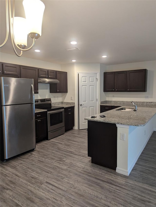 kitchen with hanging light fixtures, hardwood / wood-style flooring, kitchen peninsula, sink, and stainless steel appliances