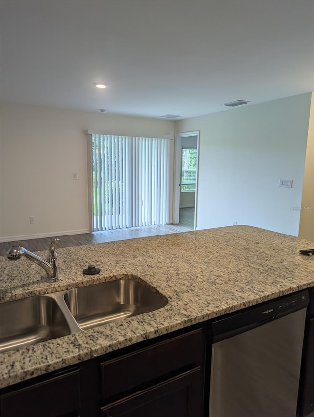 kitchen with sink, light stone counters, stainless steel dishwasher, and wood-type flooring