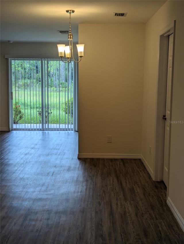 empty room featuring a notable chandelier and wood-type flooring