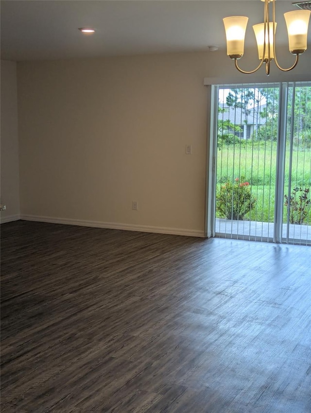 spare room featuring a healthy amount of sunlight, dark hardwood / wood-style flooring, and an inviting chandelier