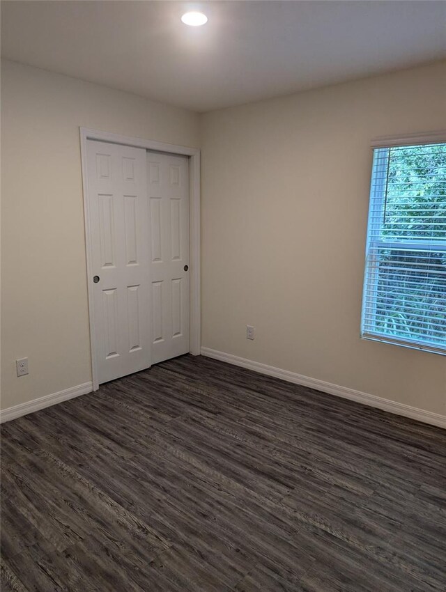 unfurnished bedroom featuring a closet and dark hardwood / wood-style flooring