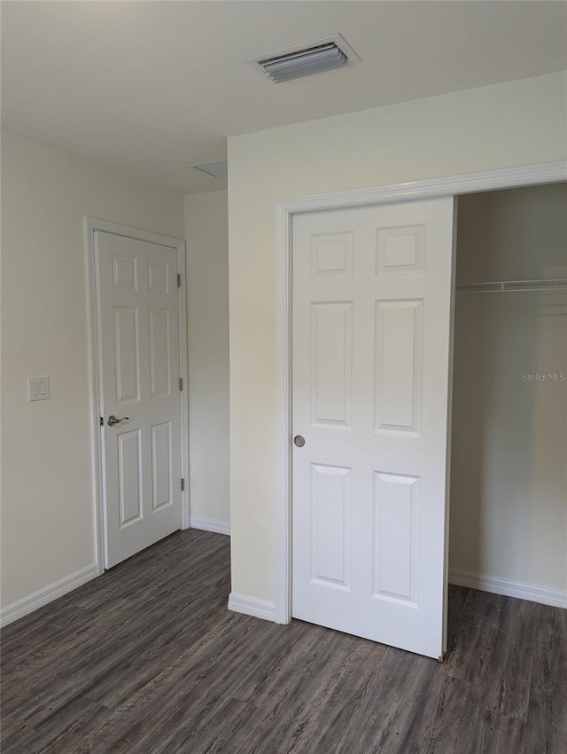 unfurnished bedroom with a closet and dark hardwood / wood-style floors