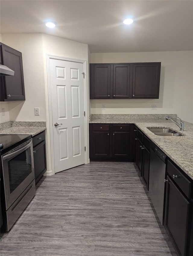 kitchen featuring appliances with stainless steel finishes, light stone countertops, light wood-type flooring, and sink