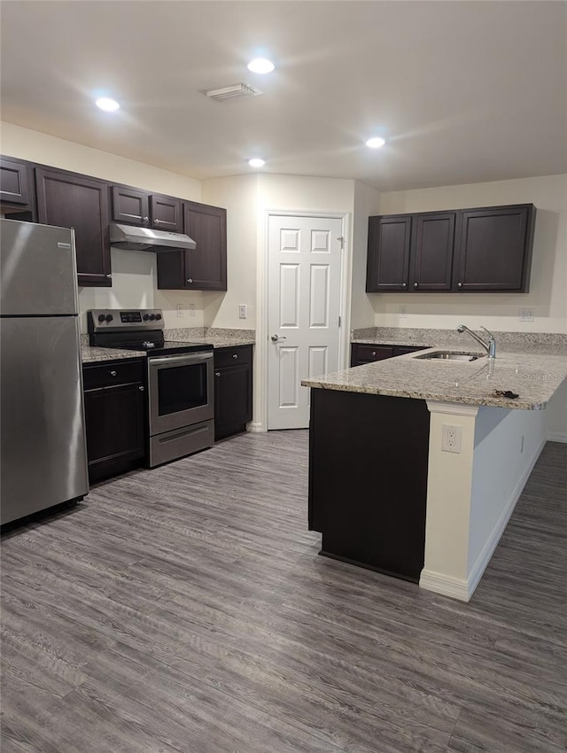 kitchen with sink, kitchen peninsula, dark wood-type flooring, stainless steel appliances, and light stone countertops