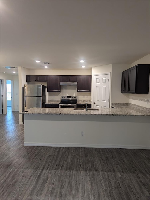 kitchen featuring appliances with stainless steel finishes, dark wood-type flooring, light stone counters, kitchen peninsula, and sink