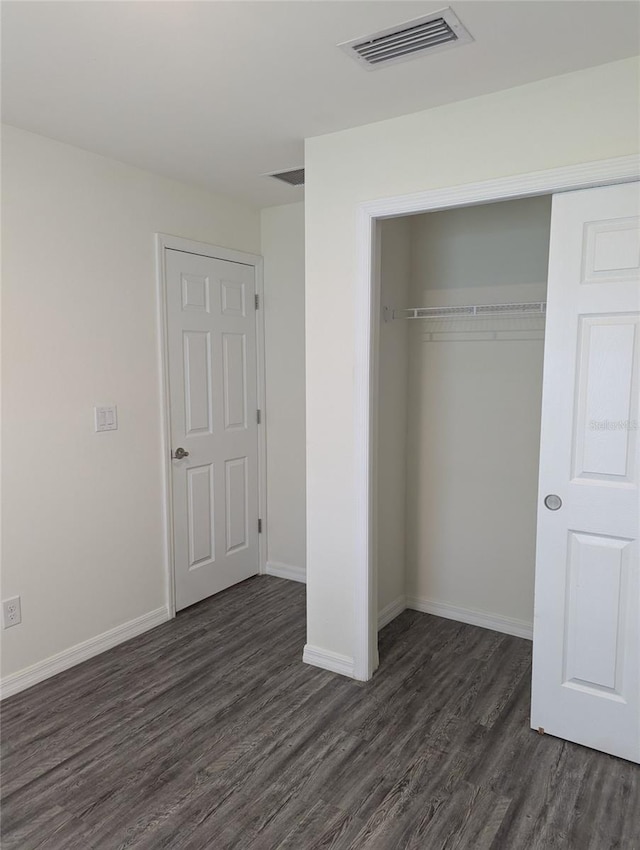 unfurnished bedroom with a closet and dark hardwood / wood-style flooring