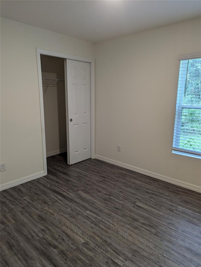 unfurnished bedroom with dark hardwood / wood-style floors and a closet