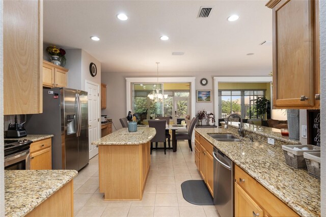 kitchen with light stone counters, a chandelier, a center island, stainless steel appliances, and sink