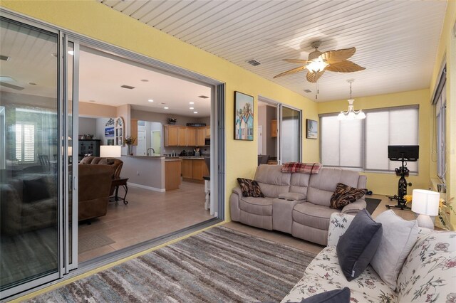 living room featuring ceiling fan with notable chandelier and tile patterned floors