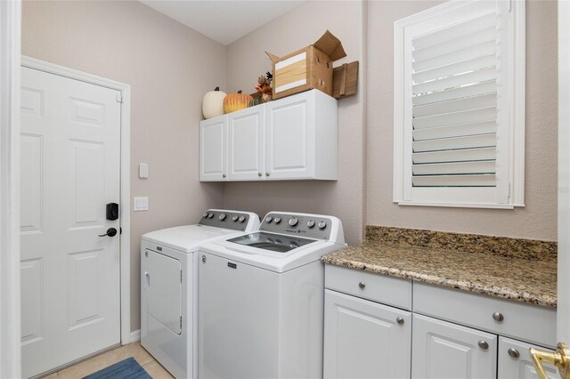 washroom featuring independent washer and dryer, light tile patterned floors, and cabinets