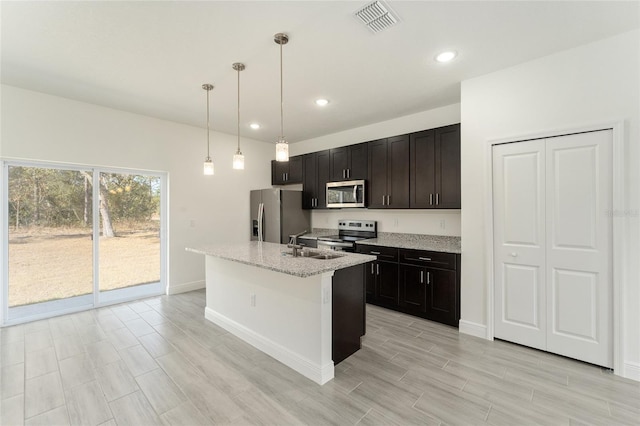 kitchen with sink, hanging light fixtures, light stone counters, a center island with sink, and appliances with stainless steel finishes